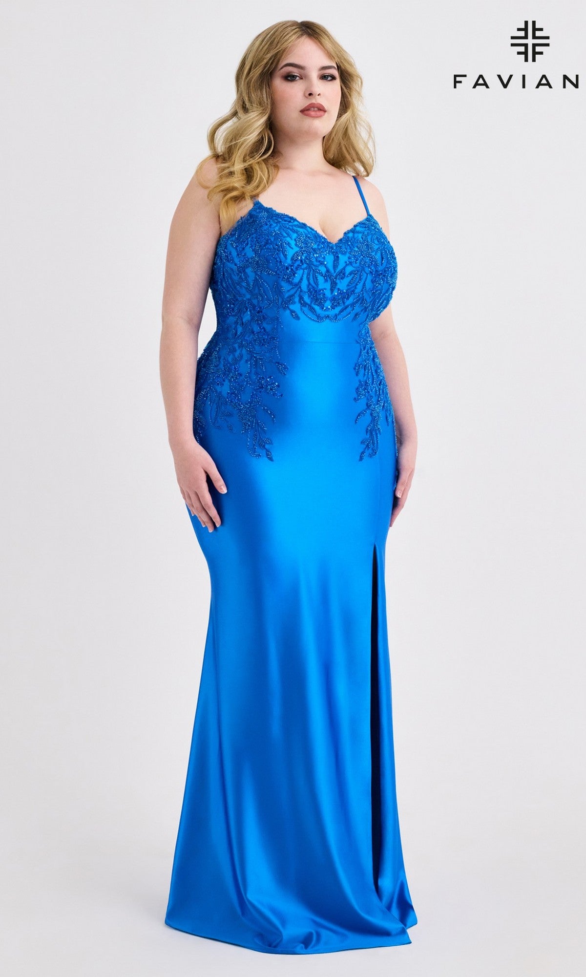 A woman models the Faviana 9603 Plus-Size Lace-Up Long Prom Dress in bright blue, featuring a beaded lace bodice and thigh-high slit, standing before a plain background with the Faviana logo in the upper right corner.